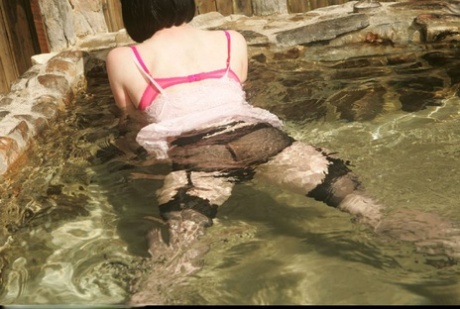 Seductive mature lady in glasses posing in the pool in her clothes 82740081